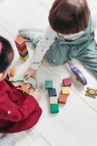 two children playing with lego blocks and other toys